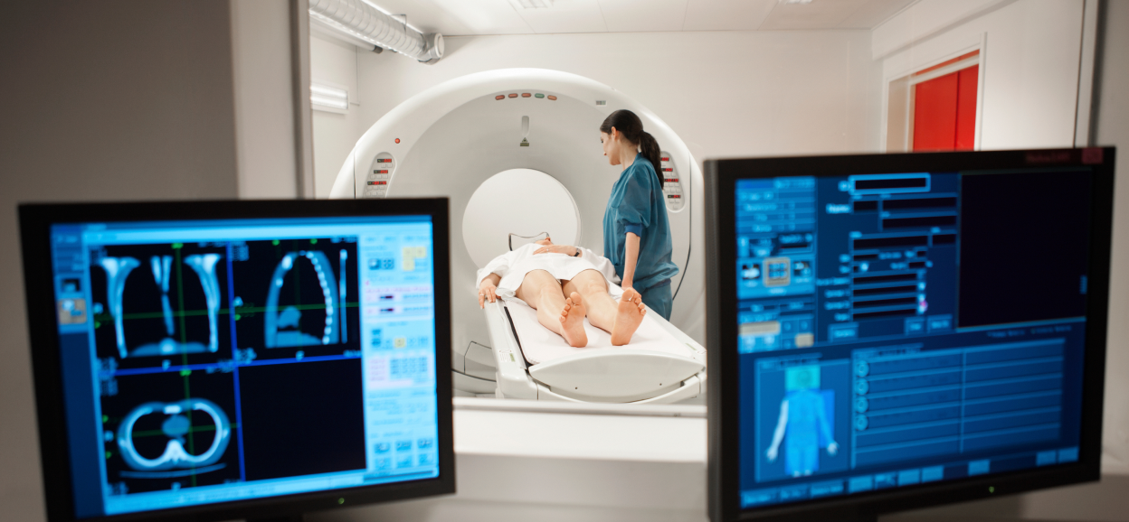 Two monitors and doctor with patient in scanner